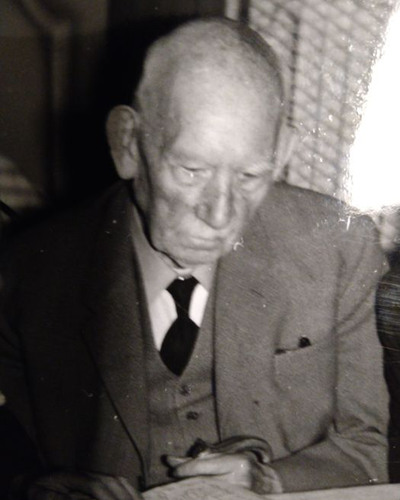 Ett svartvitt foto på en äldre man i kostym.