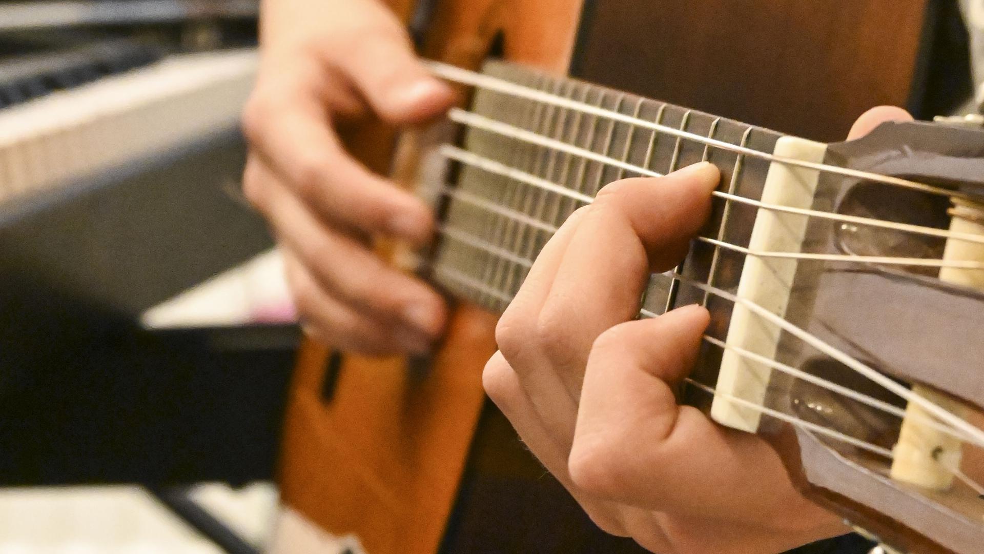 händer som spelar gitarr