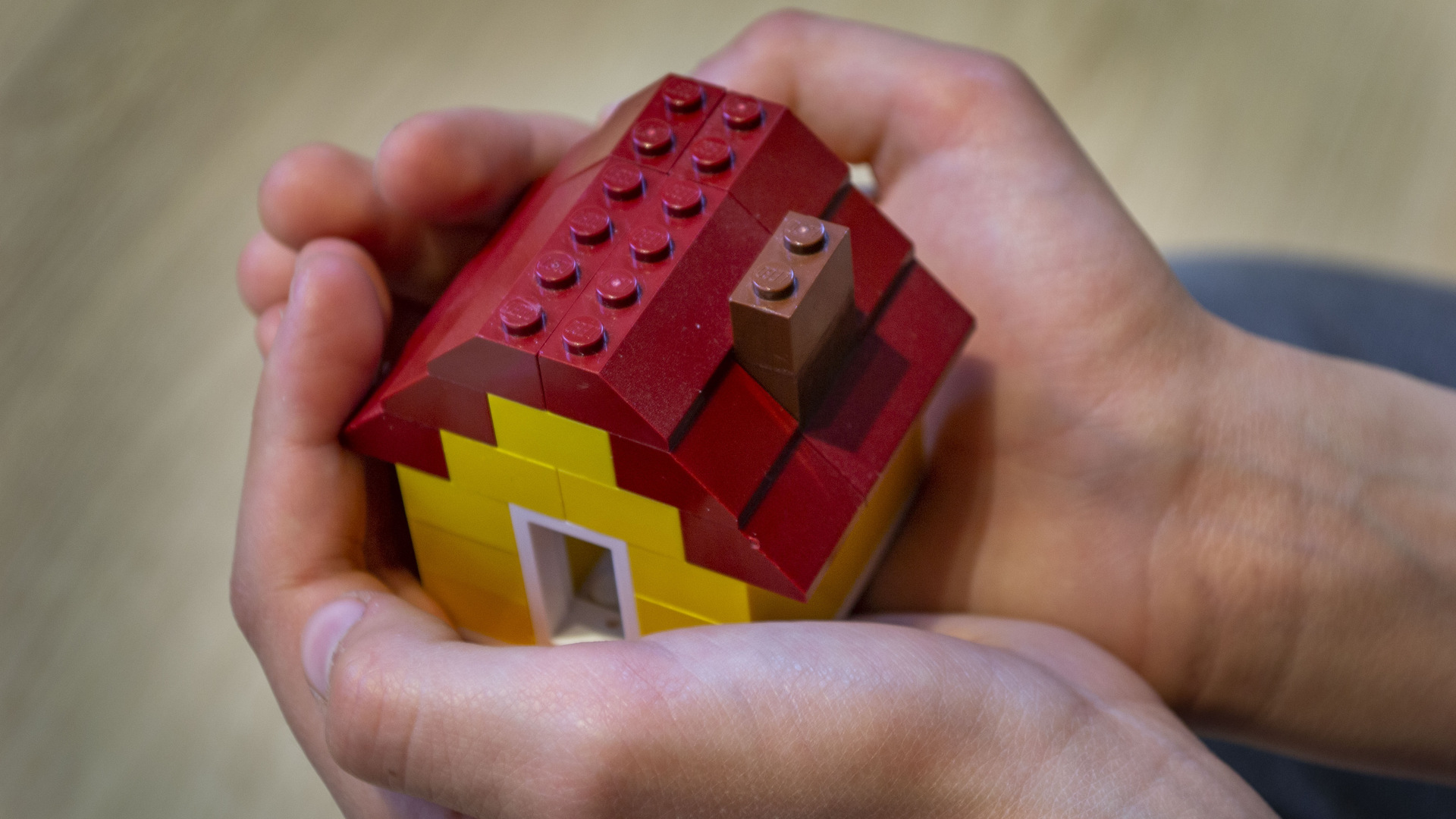 Barn håller i ett hus av lego.