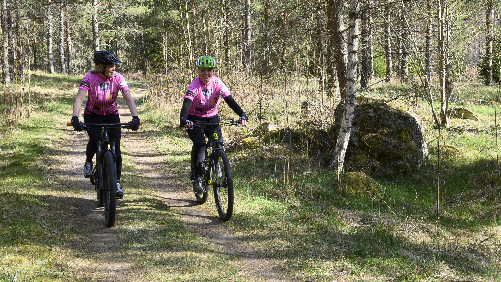 Två kvinnor cyklar i skogen i Vrigstad.