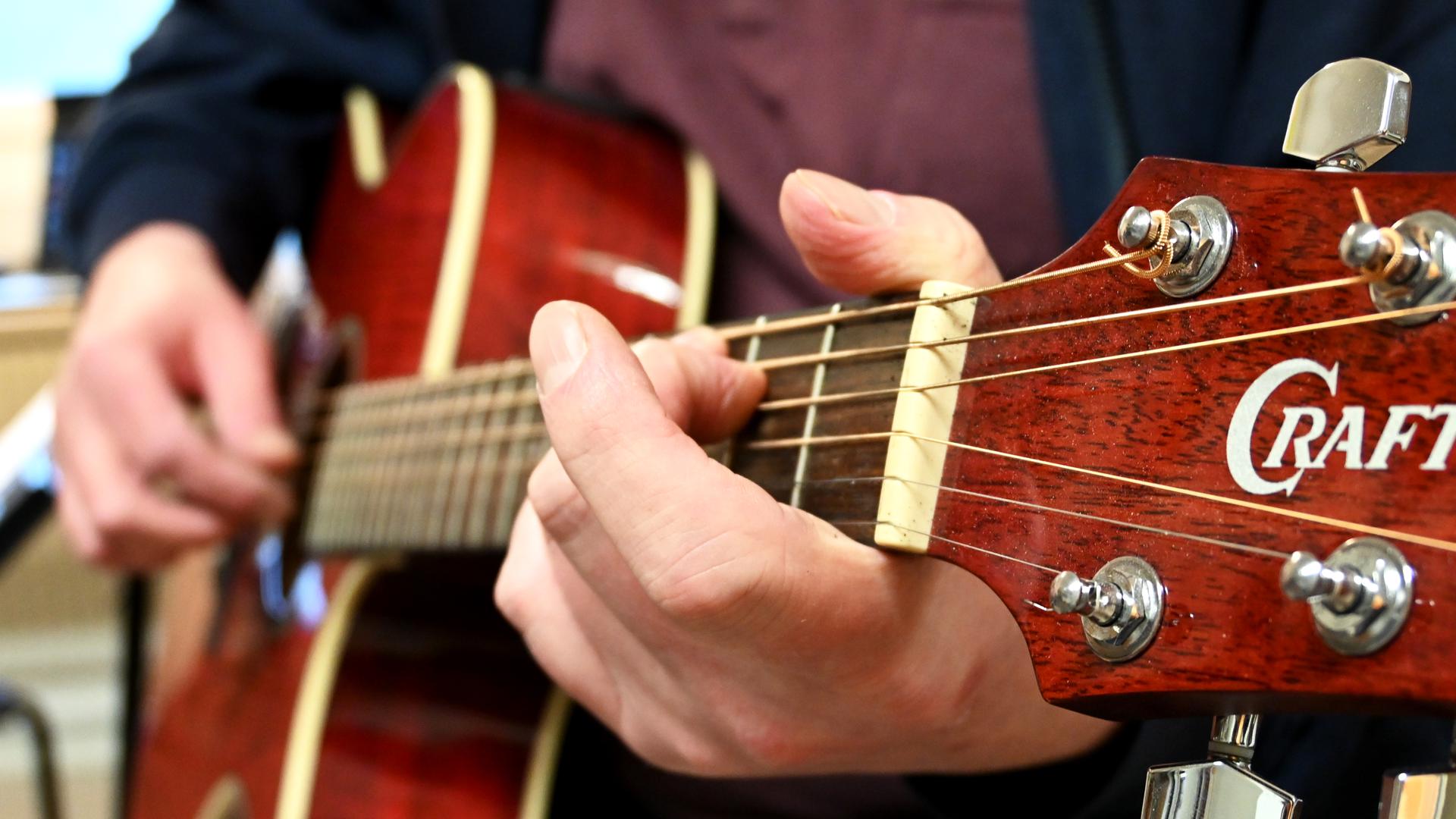 närbild på en person som spelar gitarr