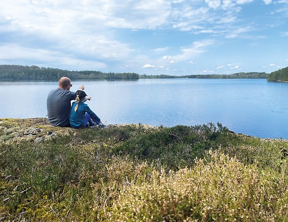 Pappa och dotter tittar ut över sjö och pekar mot vattnet.