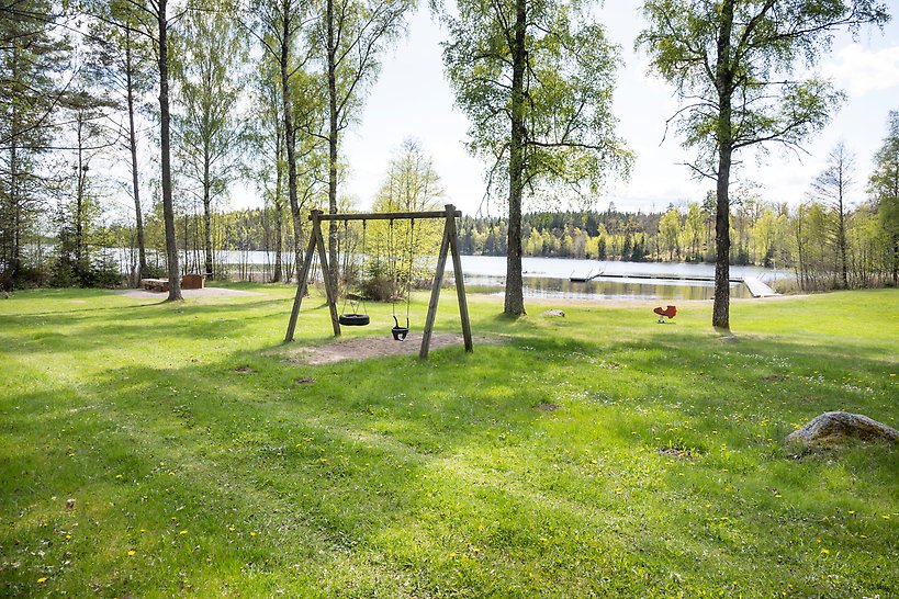 Stor gräsyta, gungor, sjö med bryggor.